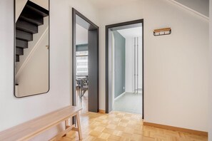 Un couloir avec un banc en bois, un miroir et un escalier.