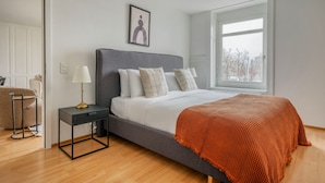 Una camera da letto moderna con un letto grande, un comodino, una lampada e una finestra.