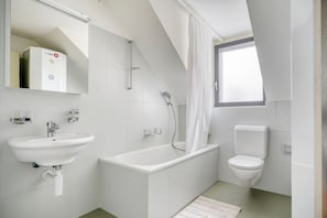 Een moderne badkamer met een badkuip, toilet en wastafel.