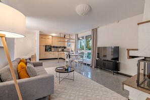 Un salon moderne avec un canapé gris, une table basse ronde et un téléviseur.