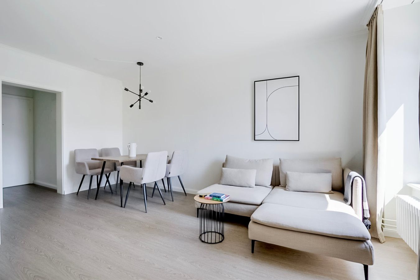 Ein modernes Wohnzimmer mit einer Couch, einem Esstisch mit Stühlen, einem Couchtisch und einer Pendelleuchte.