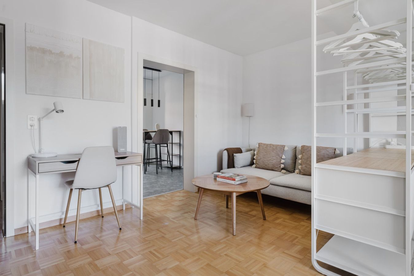 Una sala de estar moderna con un escritorio, un sofá, una mesa de centro y un vestidor.