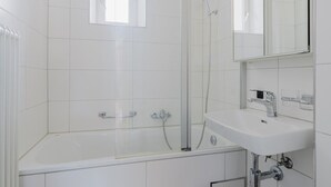 Une salle de bain moderne avec une douche à parois de verre, une baignoire blanche et un lavabo surmonté d’un miroir.