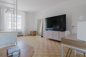 Habitació moderna i ben il·luminada amb un televisió de pantalla plana gran, una taula de menjador i una zona de seients.