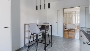 Une cuisine moderne avec un coin bar, une table à manger avec des chaises et une vue sur le salon attenant.