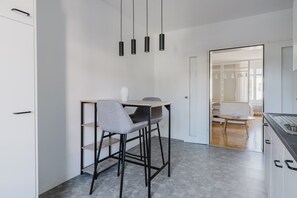 Een moderne keuken met een bar, een eettafel met stoelen en uitzicht op de aangrenzende woonkamer.