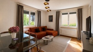 A living room with a sofa, a coffee table, a glass table with chairs, and a radiator.