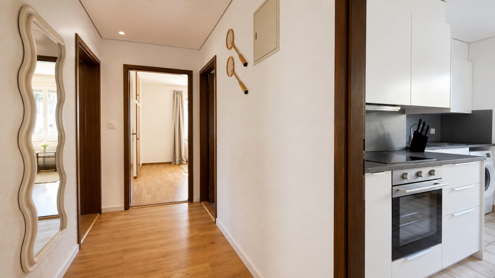 A modern kitchen with white cabinets, a built-in oven, and a countertop with a knife block.