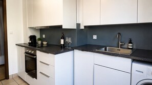 A modern kitchen with white cabinets, a built-in oven, a dishwasher, and a sink.