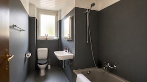 A bathroom with a toilet, sink, and bathtub. - Bright 2-BR in Wipkingen — ground floor, garden & tram nearby (Zürich)