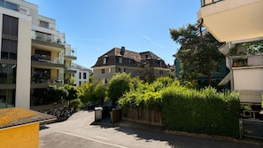 A residential street with modern and traditional houses, a clear sky, and a parked vehicle. - Bright 2-BR in Wipkingen — ground floor, garden & tram nearby (Zürich)