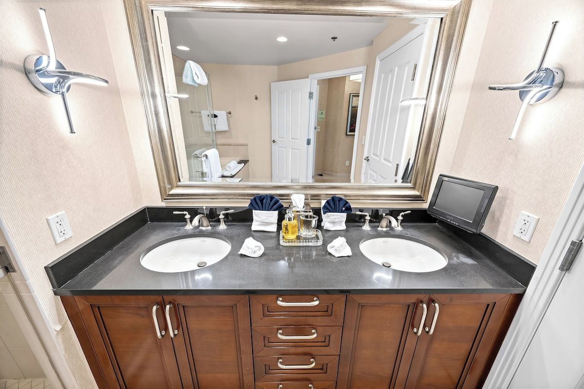 Une salle de bain avec deux lavabos, un grand miroir et un meuble avec des tiroirs.