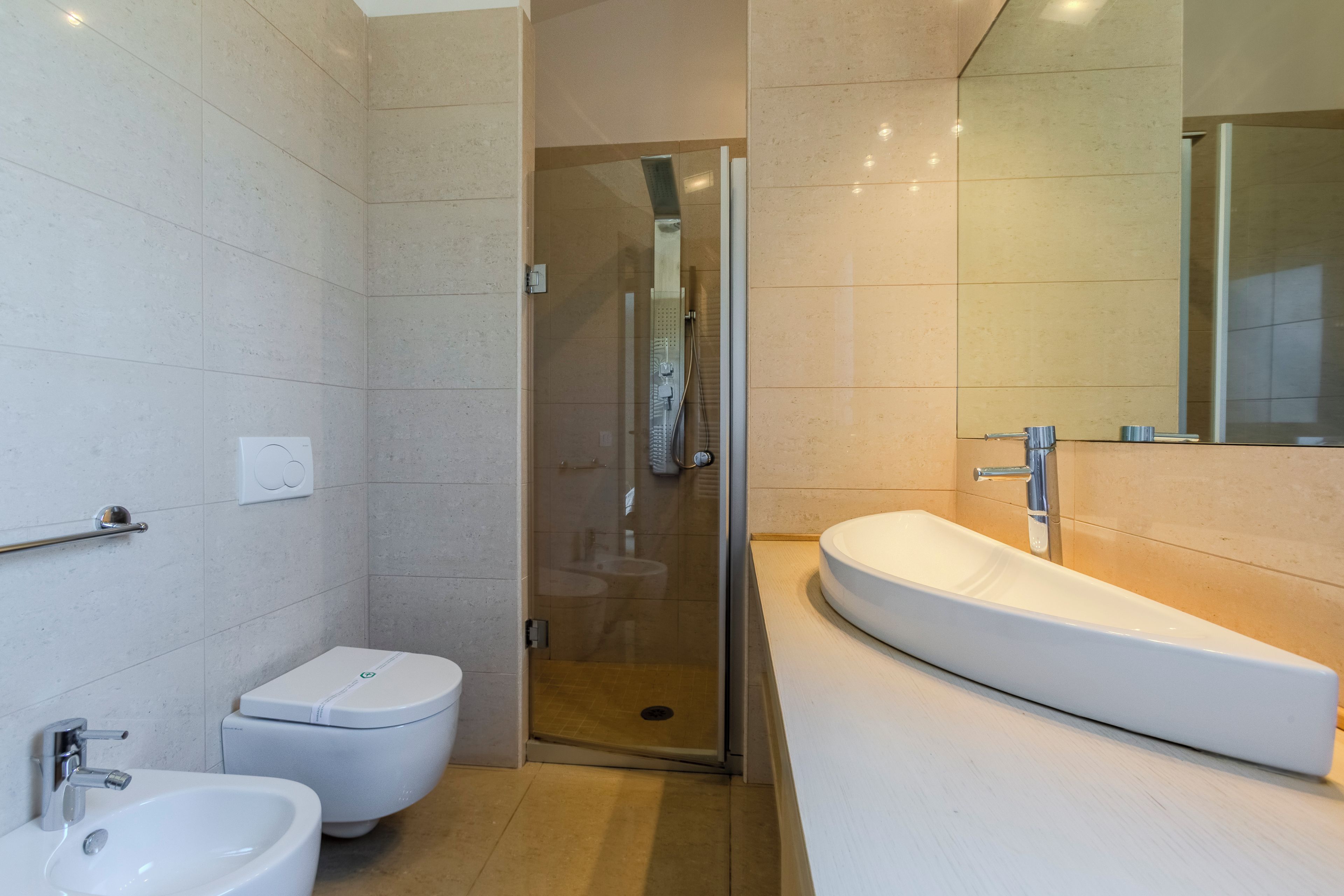 A modern bathroom with a toilet, bidet, and a large sink.