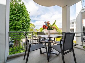 A balcony with a table and chairs, a potted plant, and a view of a residential area. - Park Residence Am Hafen 23 - \"viento\" (Zingst)