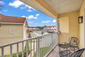 A balcony with a white railing, a table, and two chairs. - Fairytales & Galaxies | 4BR Themed Family Retreat (Kissimmee)