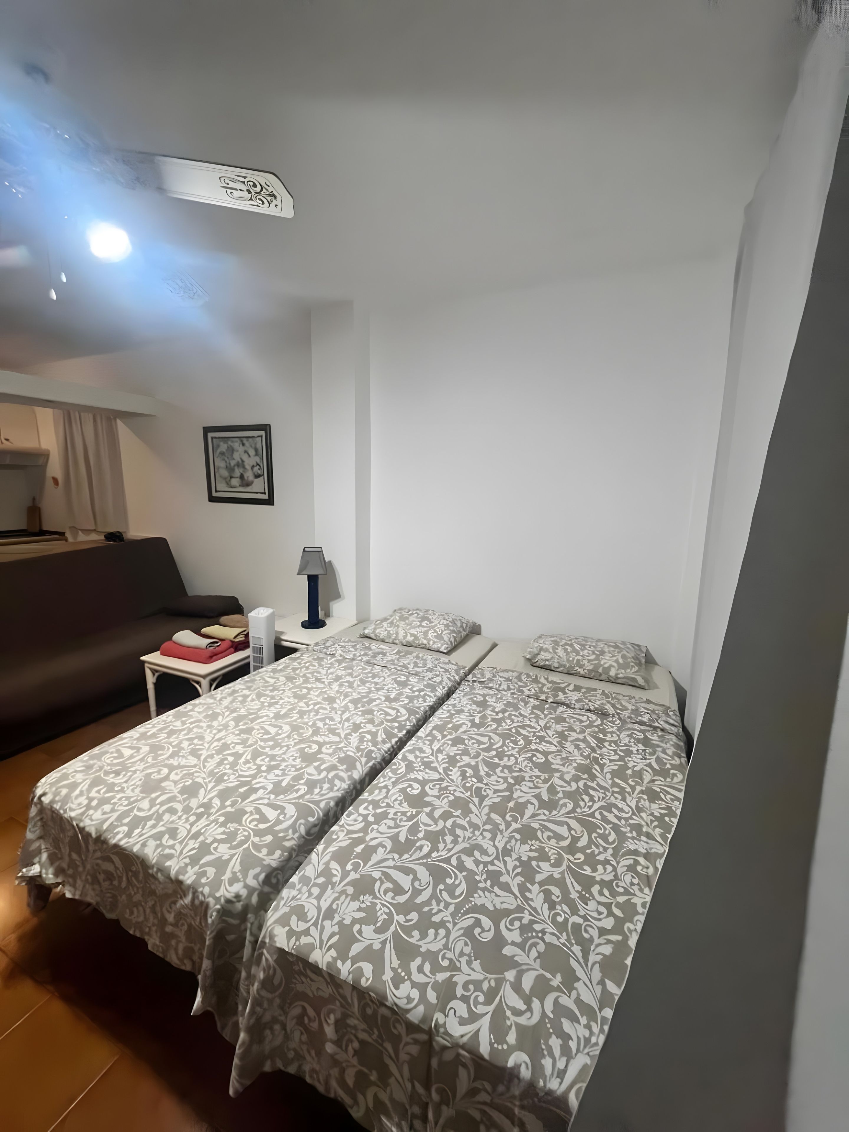 Une chambre d’hôtel avec deux lits, une petite table, une lampe et un tableau au mur.