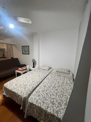 Une chambre d’hôtel avec deux lits, une petite table, une lampe et un tableau au mur.