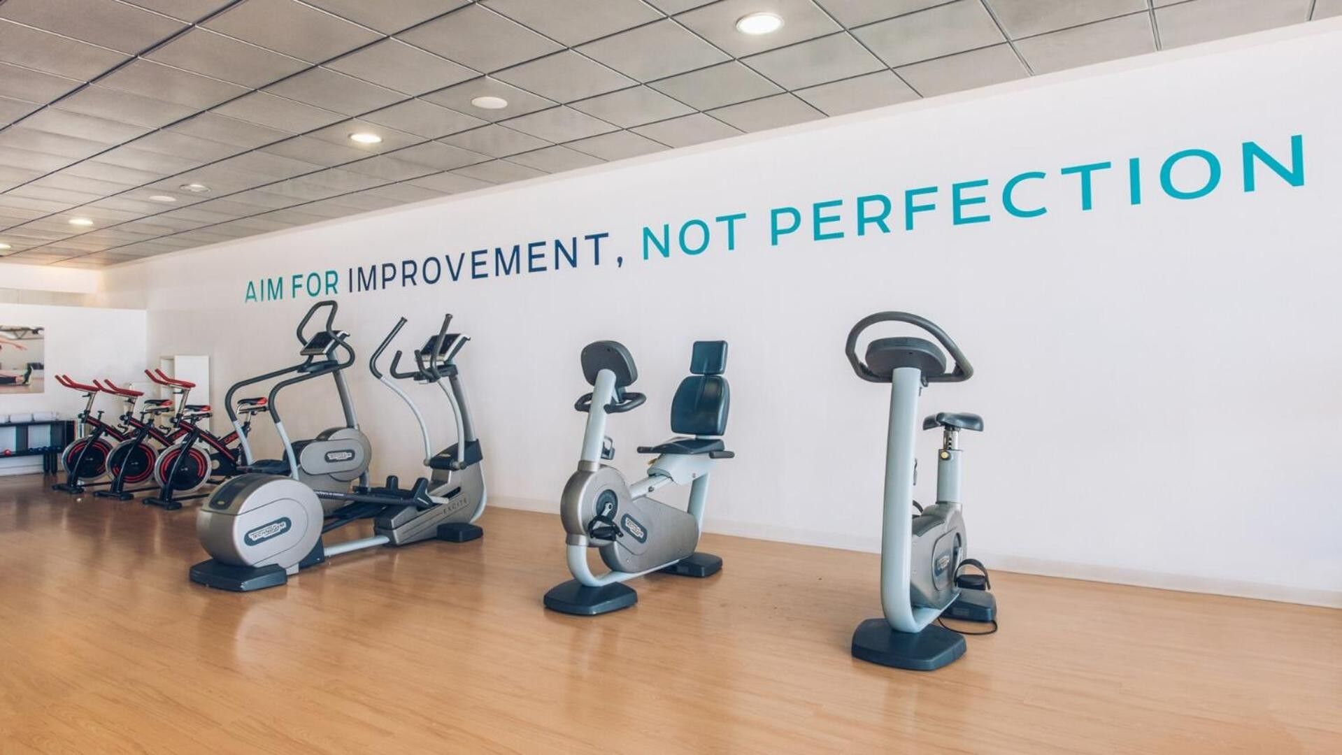 Une salle de sport équipée de vélos d’appartement et ornée d’une citation inspirante sur le mur.