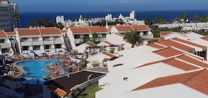 Un complexe hôtelier doté d’une piscine, de parasols de plage et offrant une vue sur l’océan.