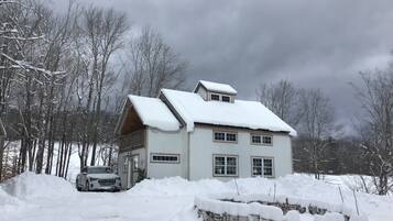 A two-story house with a snow-covered roof and a car parked in front.
