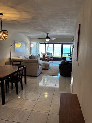 A living room with a dining area, a ceiling fan, and a view of the ocean through large windows. - Waterfront condo with sun deck and easy access to beaches & dining. (Englewood)