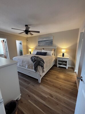 Ein Schlafzimmer mit einem Bett, Nachttischen, einem Deckenventilator und Blick aufs Meer.