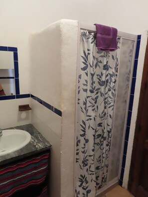 Un baño con cortina de ducha, lavamanos y espejo.