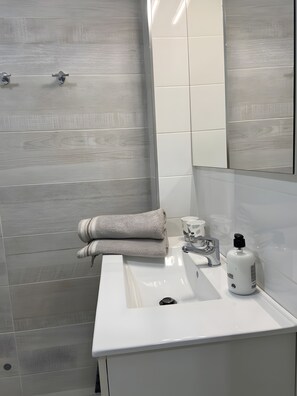 Een moderne badkamer met een witte wastafel, een spiegel en een handdoekhouder.