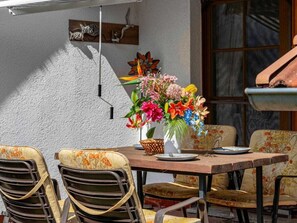 A dining area with a table and chairs, a vase of flowers, and a wall-mounted light fixture. - 6/t5 Holiday Home Park \"freesenbruch\" (Zingst)