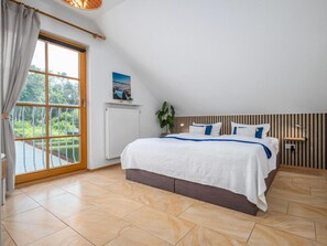 Un dormitorio con una cama grande, vistas a zonas verdes, un radiador y un cabecero de madera.