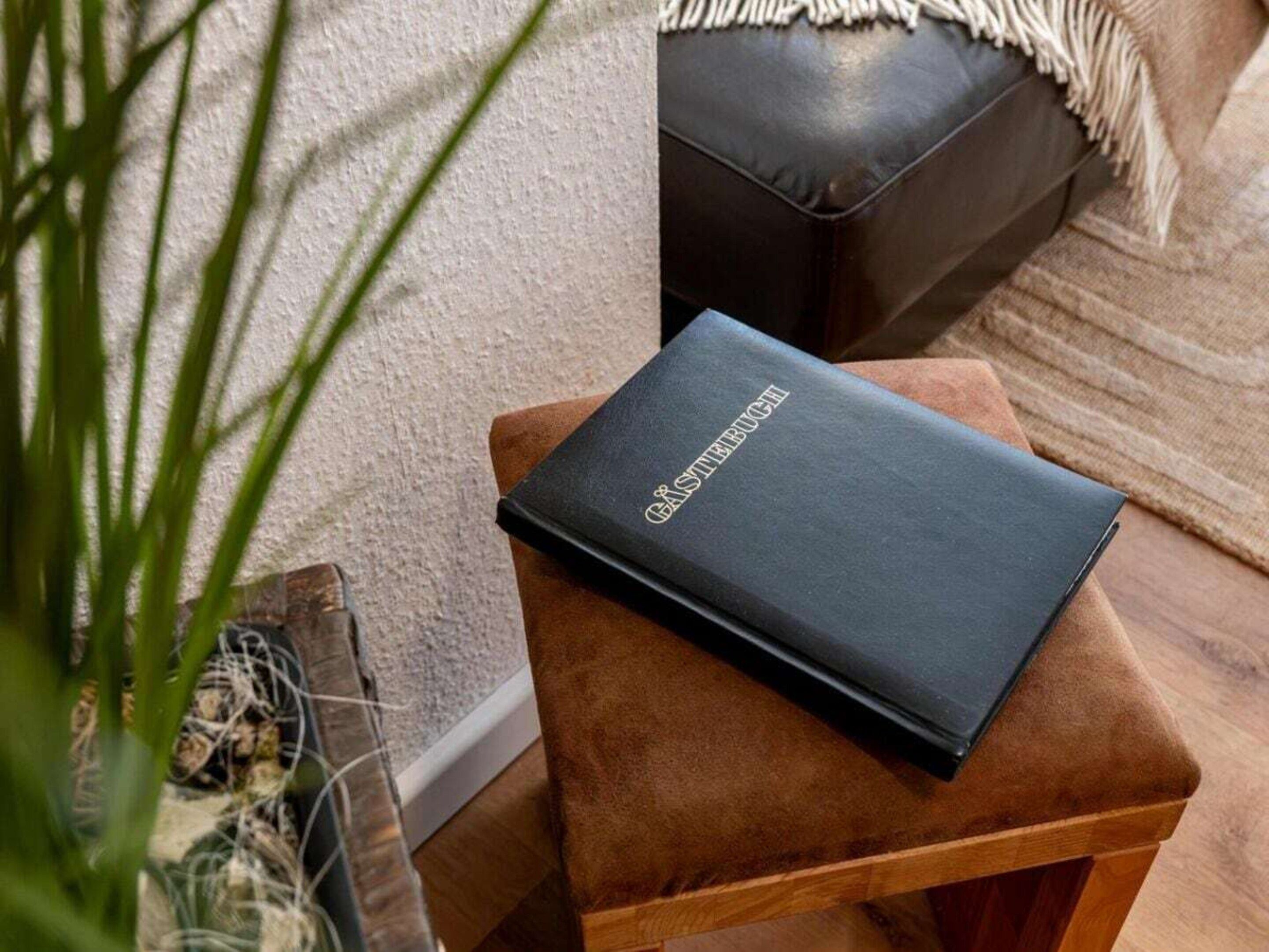 Een zwart boek met de titel 'GASTERBUCH' op een houten kruk.