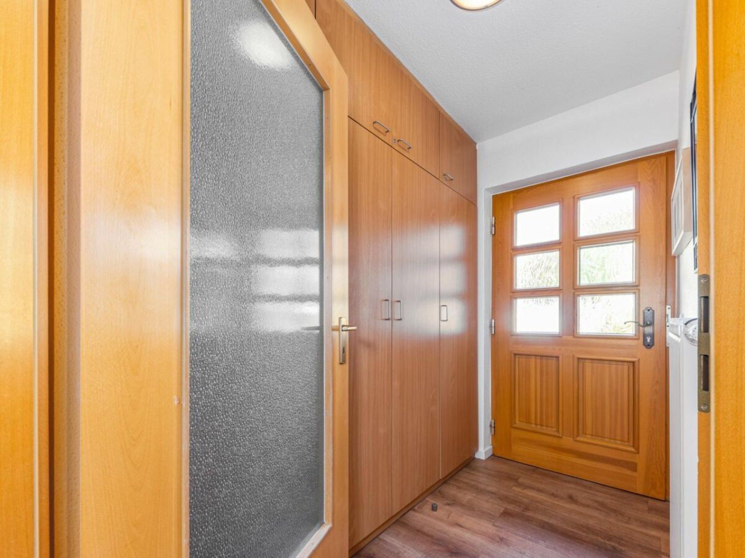 A hallway with wooden doors and a frosted glass door.