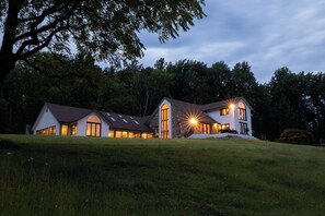 A modern two-story house with a sloped roof, large windows, and a well-maintained lawn.