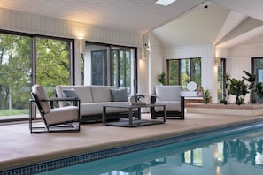 A poolside area with a sofa, chairs, and a table.