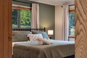 A bedroom with a bed, pillows, a lamp, and curtains.