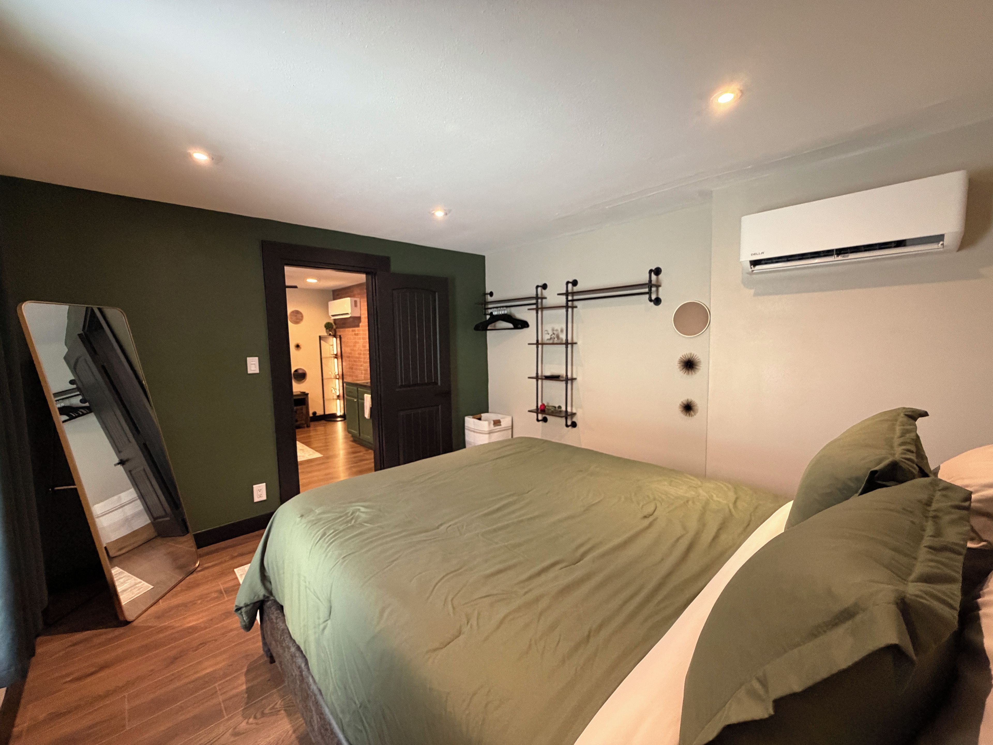 Un dormitorio con cama, armario, espejo y aire acondicionado.
