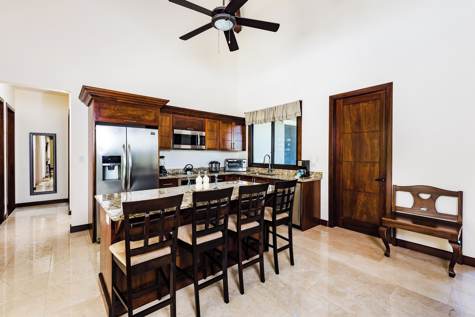 Una cocina con una isla central, armarios de madera, electrodomésticos de acero inoxidable y un ventilador de techo.