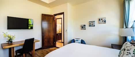 Habitación de hotel con cama, escritorio con silla, televisor y puerta que da a un baño.