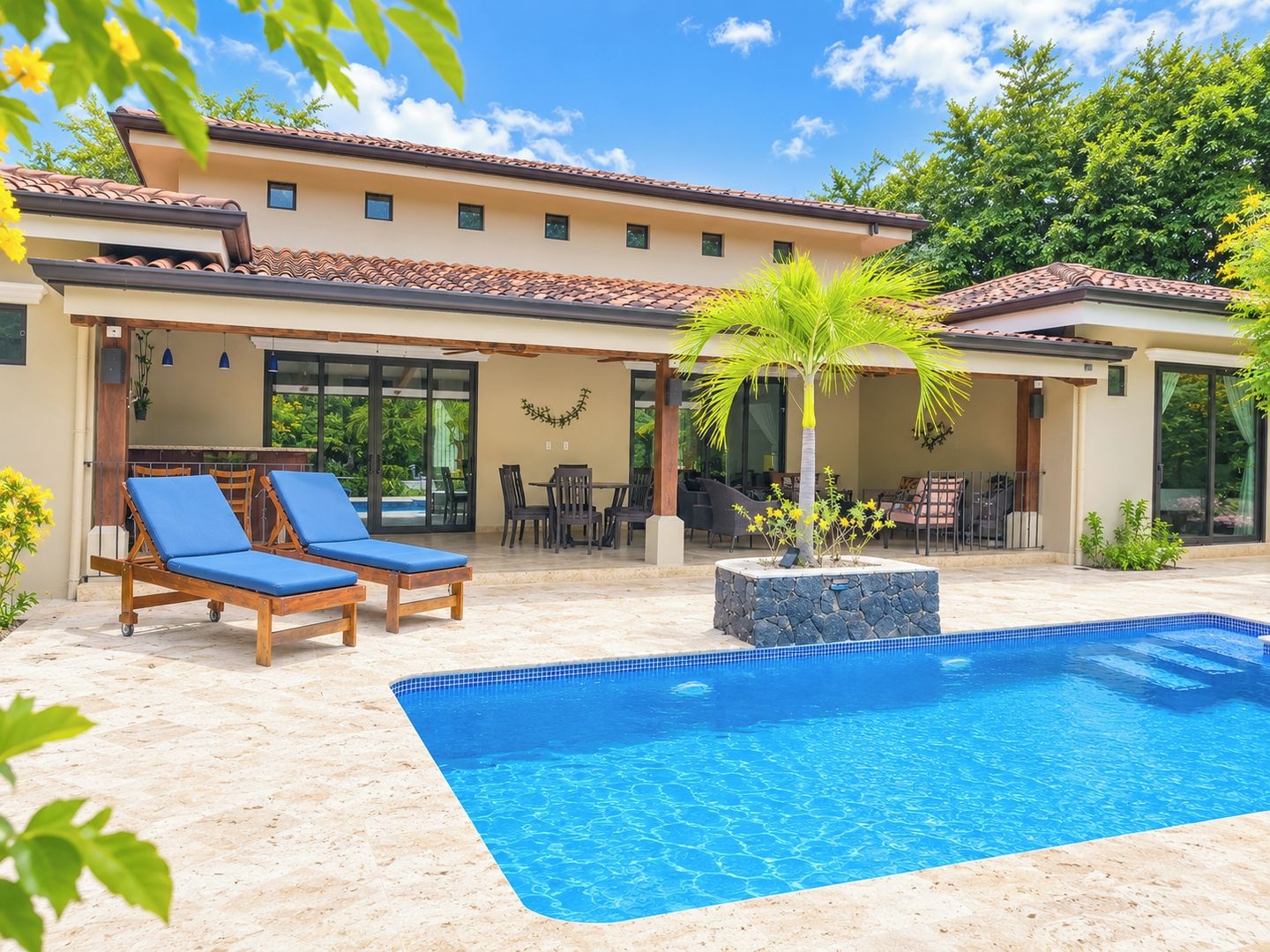 A poolside area with a swimming pool, lounge chairs, and a covered patio with outdoor furniture.