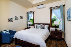 Ein Schlafzimmer mit einem Bett, Nachttischen, einem Sessel und Kunstwerken an den Wänden.