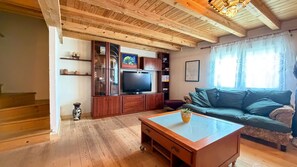 A wooden-floored living room with a television, sofa, and a coffee table. - 🌿 Iñaki's Refugio – Nature, tranquility, and vacations with your dog (Mijangos)