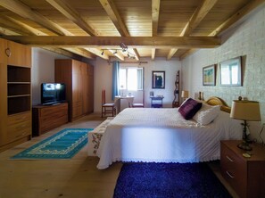 Un dormitorio con cama, armario de madera, escritorio, silla y televisor.