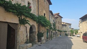 A narrow street lined with stone buildings, some with vines growing on the walls, and a parked car on the right. - 🌿 Iñaki's Refugio – Nature, tranquility, and vacations with your dog (Mijangos)