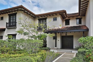 A two-story building with a covered entrance, multiple windows, and a balcony. - 3-Bedroom Villa in Hacienda Pinilla (Pinilla)