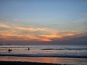 A beach with calm waters and a sunset sky. - Casa Pochote | Hacienda Pinilla | Golf and Beach (Pinilla)