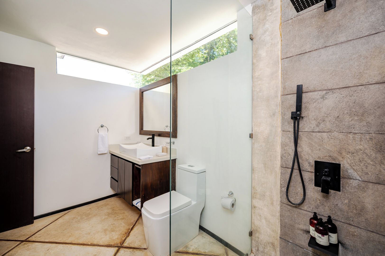 Een moderne badkamer met een douchecabine van glas, een wit wastafelmeubel en een toilet.