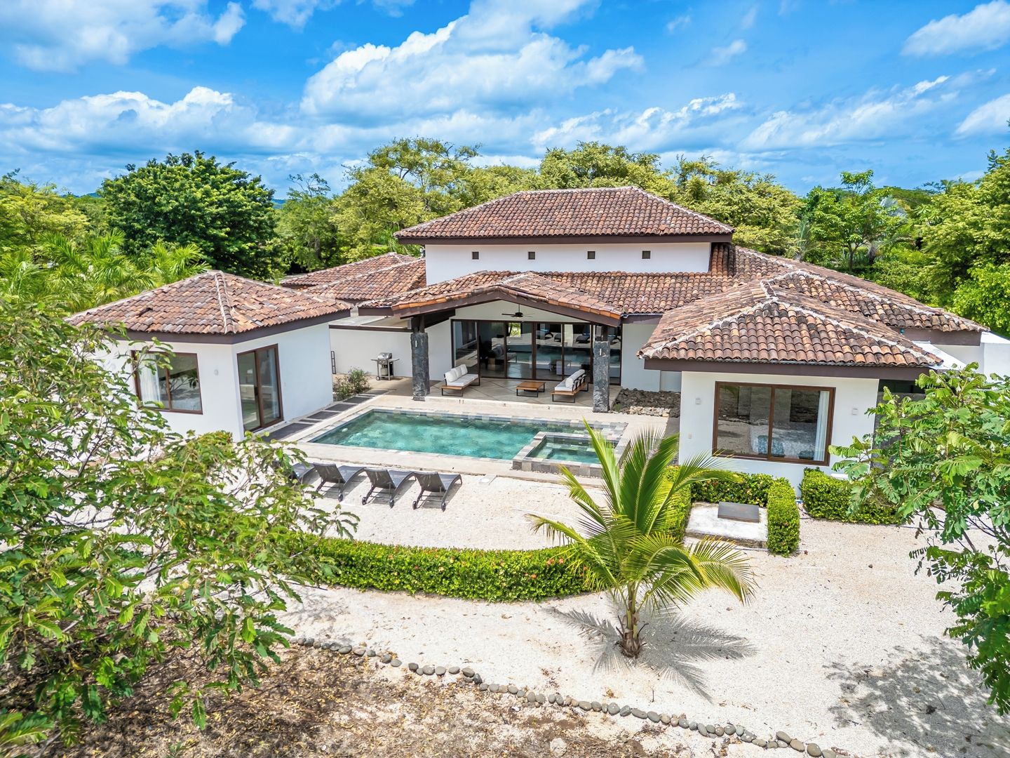 A two-story house with a swimming pool, surrounded by greenery.