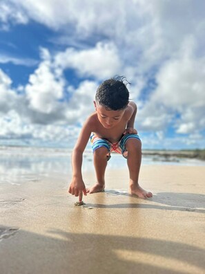 A child playing on a sandy beach with a clear sky in the background. - Casa Solara | Hacienda Pinilla (Hacienda Pinilla)