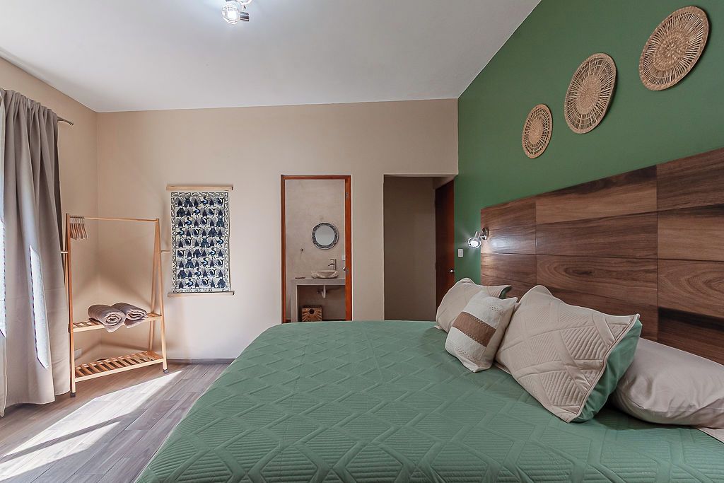 A bedroom with a green bedspread, wooden headboard, and a wooden wardrobe.