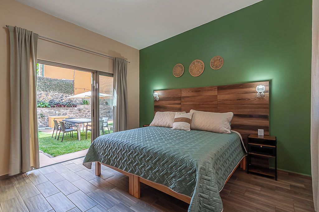 A bedroom with a large bed, a wooden headboard, and a view of an outdoor patio.
